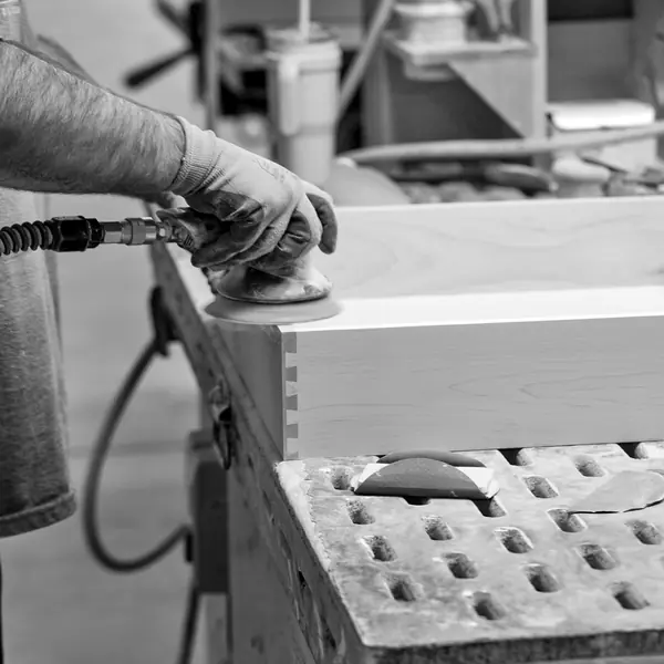 A craftsman sands a drawer box on the line